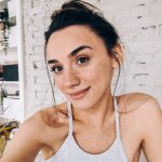 Photo of a smiling freckled woman sitting on a couch indoors.